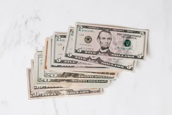Pile of U.S. dollar bills of different denominations on a marble surface