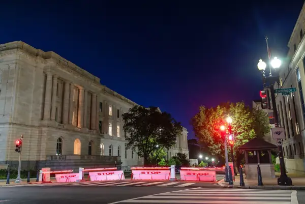 Russell and Dirksen Senate office buildings at night with red STOP barriers on the street