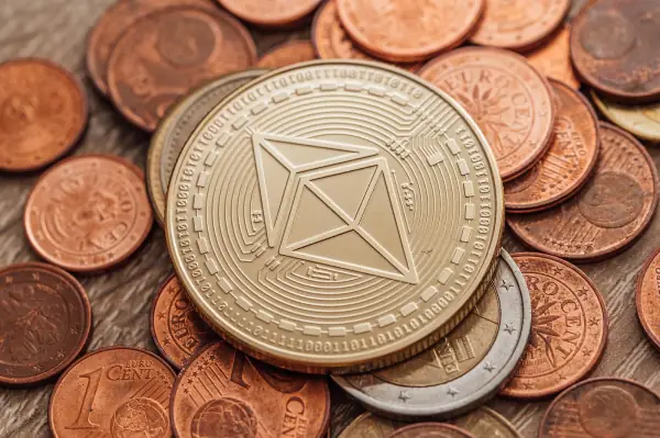 Close-up of a physical Ethereum coin resting on a pile of regular coins