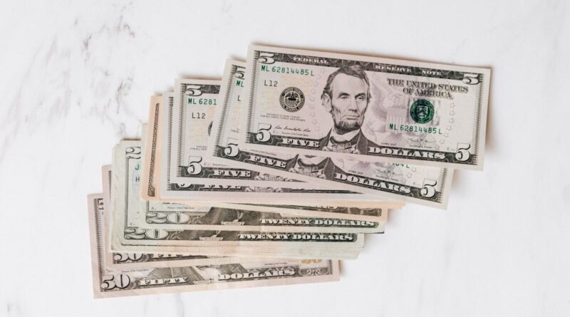 Pile of U.S. dollar bills of different denominations on a marble surface