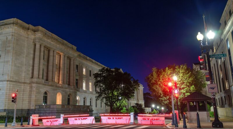 Russell and Dirksen Senate office buildings at night with red STOP barriers on the street