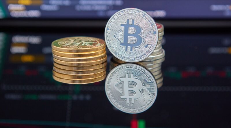 Stacked bitcoin coins in front of a red and green trading chart