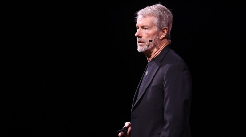Michael Saylor in profile on a dark stage at Bitcoin 2025